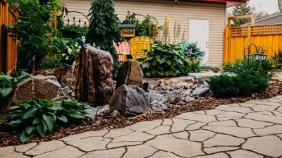 Landscaped backyard with water feature and patio. Photo